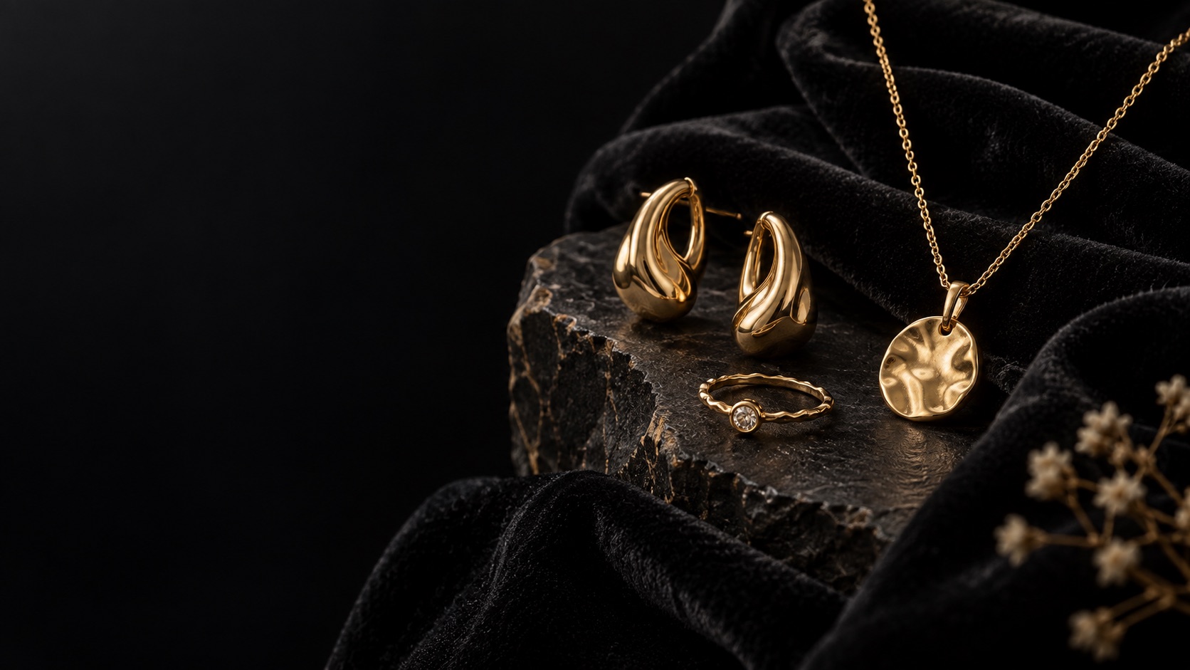 Gold jewelry arranged over black velvet and stone
